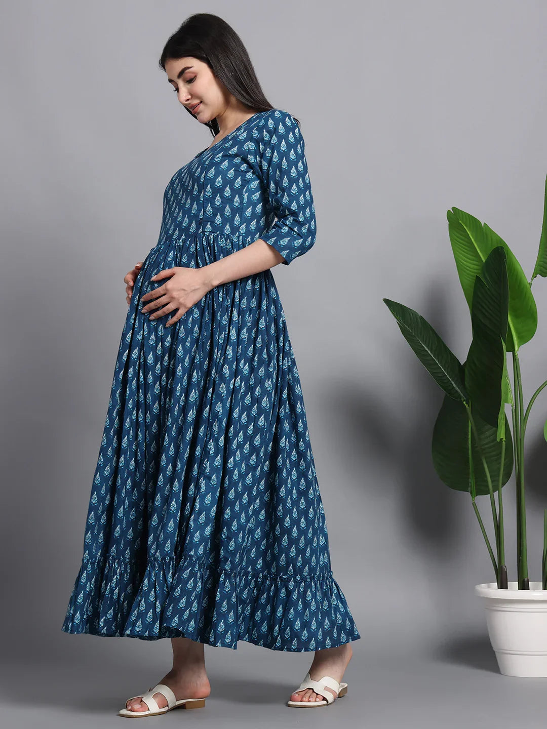 Pregnant woman wearing blue printed maternity maxi dress with three-quarter sleeves, side view