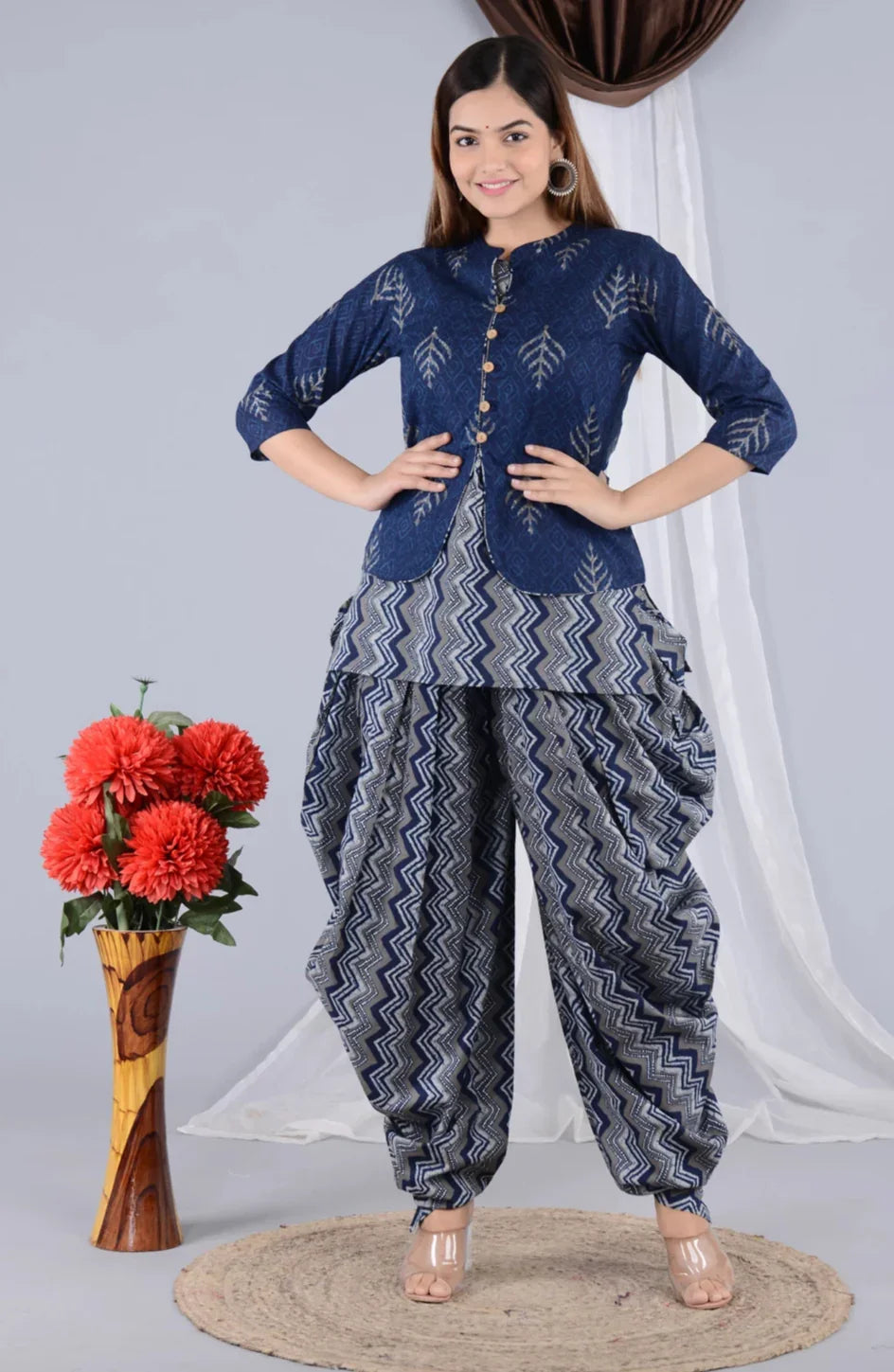 Woman wearing a blue printed kurta with zigzag patterned dhoti pants, standing indoors