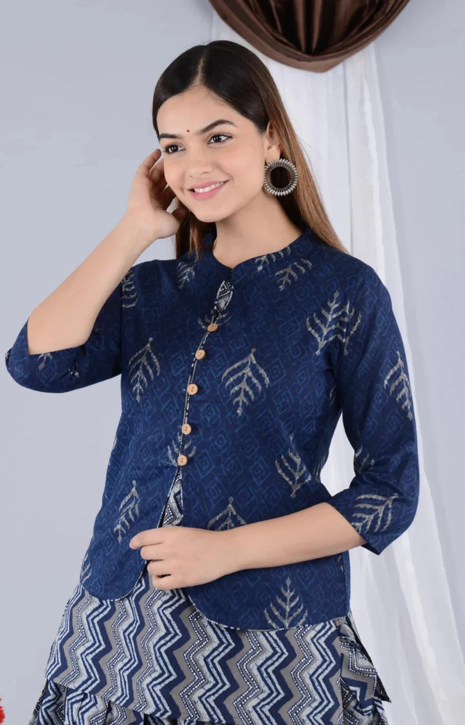 Woman wearing blue maternity kurta with leaf patterns and wooden buttons, smiling indoors